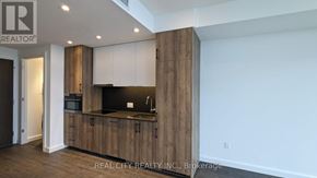 Kitchener condo for rent - A modern kitchen with wooden cabinets and a black countertop.
