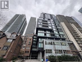 Toronto (Church-Yonge Corridor) condo for rent - A tall building with a glass facade stands in front of other buildings.