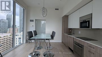 Toronto (Church-Yonge Corridor) condo for rent - A modern kitchen with a dining table and chairs in front of a large window.