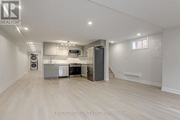 Toronto (Briar Hill-Belgravia) apartment for rent - A spacious kitchen with white cabinets and a wooden floor.