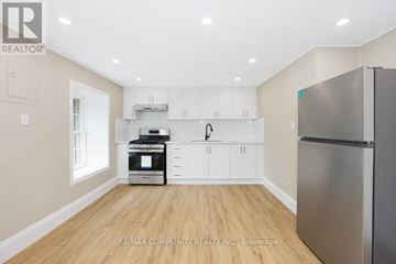 Cambridge fourplex for rent - A kitchen with white cabinets and a stainless steel refrigerator.