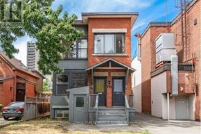 Ottawa triplex for rent - A two-story house with a grey front yard and a red brick wall.