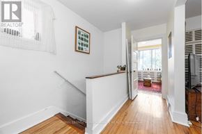 Ottawa triplex for rent - A white room with a wooden floor and a staircase leading to the second floor.