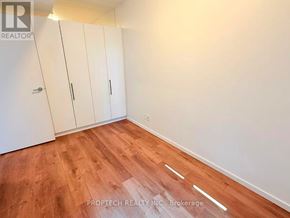 Toronto (North Riverdale) multi-family for rent - A room with wooden flooring and white walls, featuring a set of white cupboards.