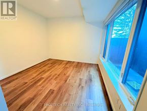 Toronto (North Riverdale) multi-family for rent - A room with wooden flooring and a window showing trees outside.