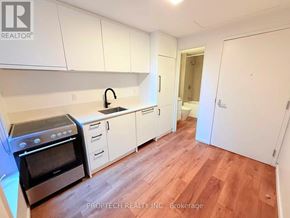 Toronto (North Riverdale) multi-family for rent - A kitchen with white cabinets and a black stove top oven.