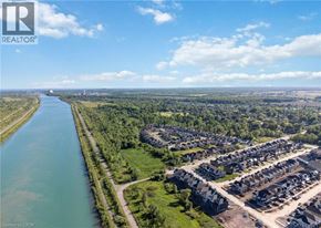 Welland apartment for rent - A river flows through a green landscape next to a housing development.