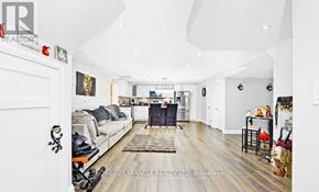 Bradford West Gwillimbury (Bradford) apartment for rent - A well-lit, spacious living room with a grey sofa and a wooden floor.