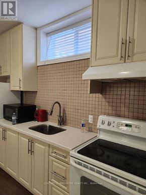 Toronto (Scarborough Village) apartment for rent - A kitchen with a white stove top oven and a black microwave.