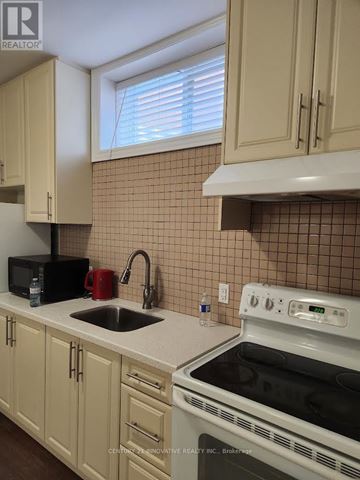 Toronto (Scarborough Village) apartment for rent - A kitchen with a white stove top oven and a black microwave.