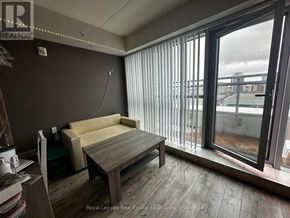 Waterloo condo for rent - A room with a couch, a table, and a window with blinds.