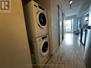 Waterloo condo for rent - A Royal LePage Real Estate Associates brokerage logo is on a wall in a room with a washer and dryer stacked on top of each other.