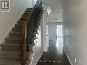Southgate apartment for rent - A staircase with a wooden handrail and a carpeted runner.