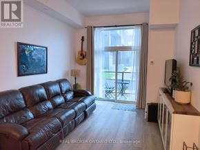 Hamilton (Waterdown) condo for rent - A living room with a brown leather couch and a guitar hanging on the wall.