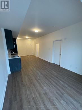 Clarington (Bowmanville) condo for rent - A spacious room with wooden flooring and white walls.