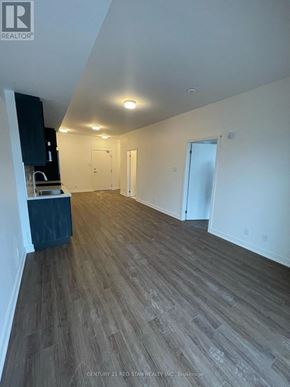 Clarington (Bowmanville) condo for rent - A room with wooden flooring and white walls, with a cabinet and a countertop on the left side.