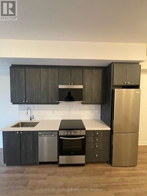 Clarington (Bowmanville) condo for rent - A modern kitchen with dark wood cabinets and stainless steel appliances.