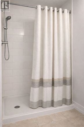 Casselman apartment for rent - A white shower curtain with grey stripes hangs in a white tiled shower.