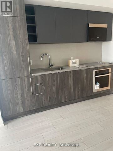 Toronto (Agincourt South-Malvern West) condo for rent - A modern kitchen with dark wood cabinets and a white countertop.