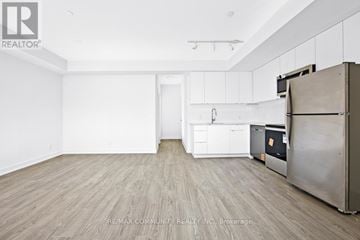 St. Catharines (E. Chester) townhouse for rent - A kitchen with white cabinets and a wooden floor.