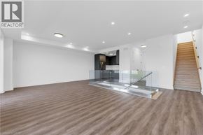 St. Catharines townhouse for rent - A spacious room with wooden flooring and a staircase.