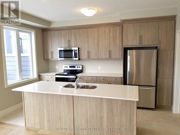 London East (East D) townhouse for rent - A kitchen with a stainless steel refrigerator and wooden cabinets.