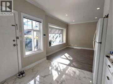Vancouver apartment for rent - A spacious kitchen with white marble flooring and a refrigerator on the right side.