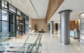 Toronto (Bayview Village) condo for rent - A spacious office lobby with a glass railing and a person standing in the background.