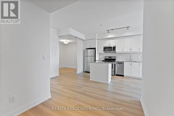 Toronto (Bayview Village) condo for rent - A spacious kitchen with white cabinets and a wooden floor.