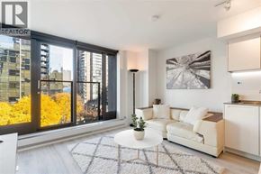 Vancouver apartment for rent - A living room with a white couch and a large window with a view of the city.