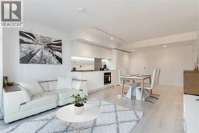 Vancouver apartment for rent - A modern living room with a white sofa, a dining table with chairs, and a kitchen area in the background.