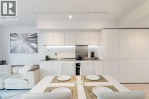 Vancouver apartment for rent - A modern kitchen with white cabinets and a dining table set for two.