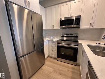Edmonton apartment for rent - A kitchen with a stainless steel refrigerator and white cabinets.