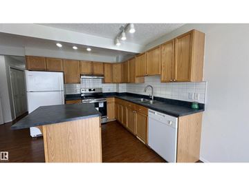 Edmonton duplex for rent - A kitchen with wooden cabinets and a black countertop.