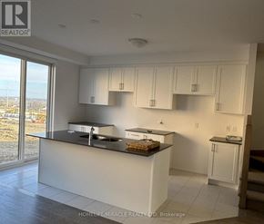 South-West Oxford townhouse for rent - A kitchen with white cabinets and a large island.