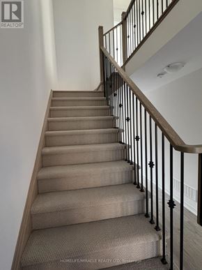 South-West Oxford townhouse for rent - A staircase with a beige carpeted runner and black metal balusters.