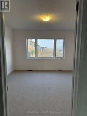 South-West Oxford townhouse for rent - A room with a carpeted floor and a window overlooking a construction site.