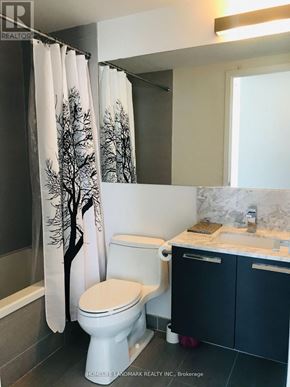Toronto (Church-Yonge Corridor) condo for rent - A white toilet with a tree patterned shower curtain in a bathroom.