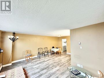 Toronto (Victoria Village) condo for rent - A living room with a dining table set up with chairs and a person sitting at the table.
