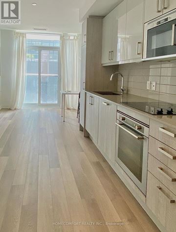 Toronto (Moss Park) condo for rent - A kitchen with white cabinets and a wooden floor.