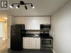 Welland apartment for rent - A kitchen with white cabinets and black appliances.