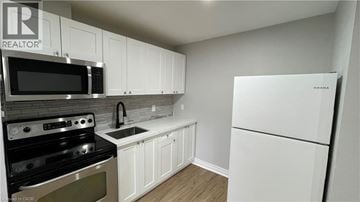 Welland apartment for rent - A kitchen with white cabinets and a white fridge.