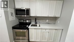 Welland apartment for rent - A kitchen with white cabinets and a black countertop.