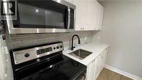 Welland apartment for rent - A kitchen with a black stove top oven and a microwave above it.