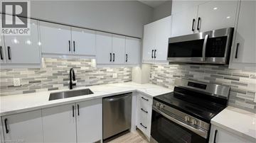 Welland apartment for rent - A modern kitchen with white cabinets and stainless steel appliances.
