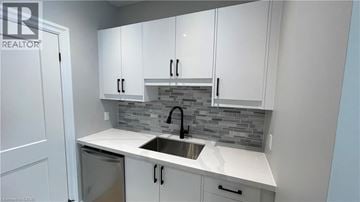 Welland apartment for rent - A kitchen with white cabinets and a grey backsplash.