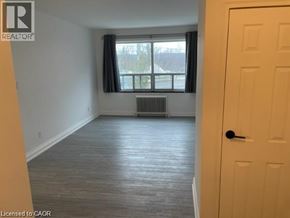 Hamilton condo for rent - A room with a door and a window with a view of a tree.