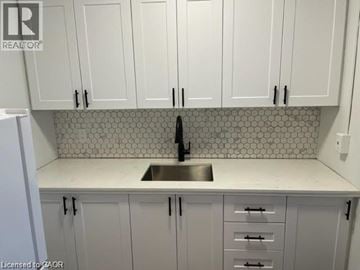 Hamilton condo for rent - A kitchen with white cabinets and a tiled backsplash.