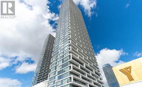 Vaughan (Vaughan Corporate Centre) condo for rent - A tall building with a glass facade stands under a blue sky with clouds.