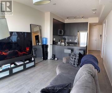 Toronto (Islington-City Centre West) condo for rent - A modern living room with a grey couch and a flat screen TV.